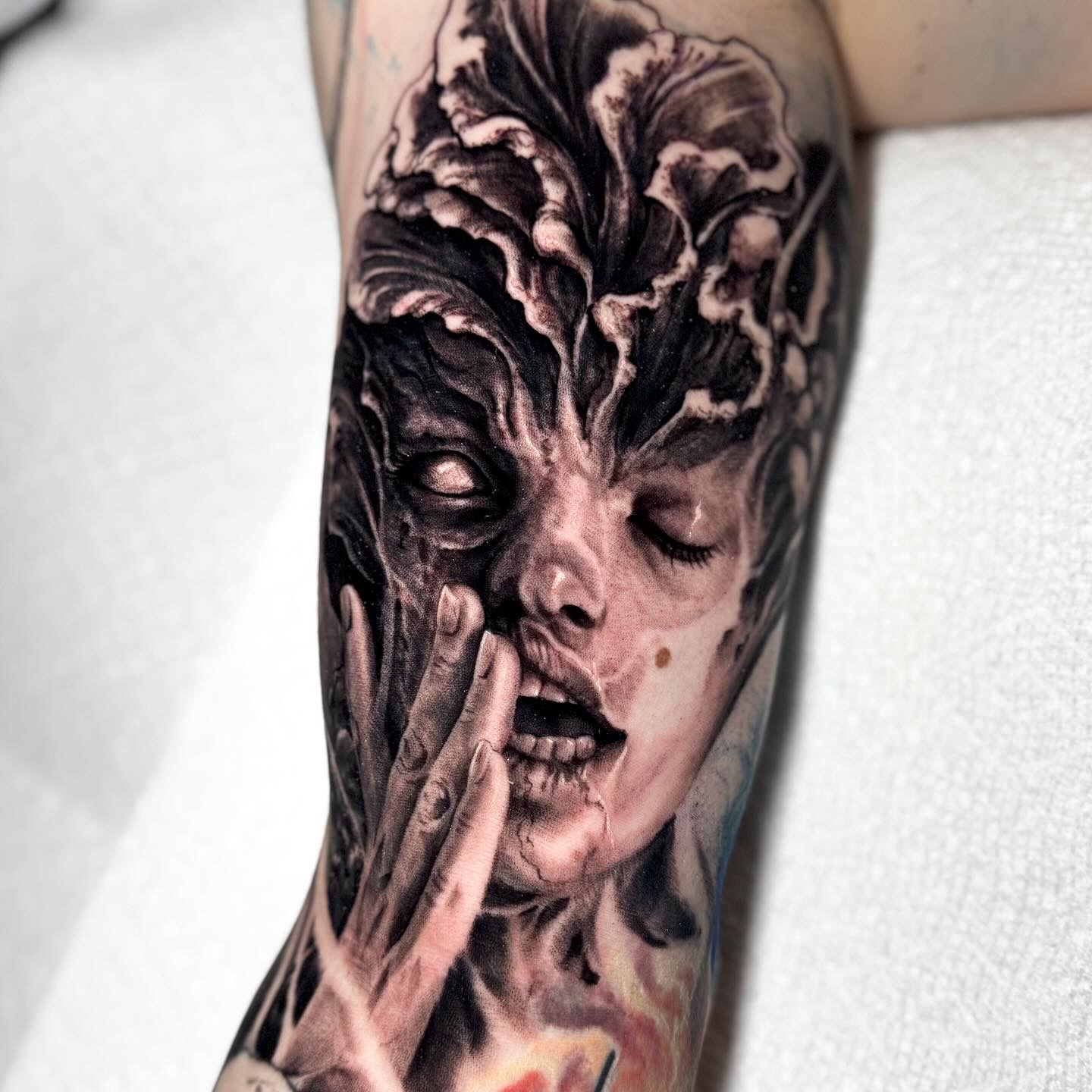 Black-and-grey haunting face forearm tattoo by Andrew Stopay
