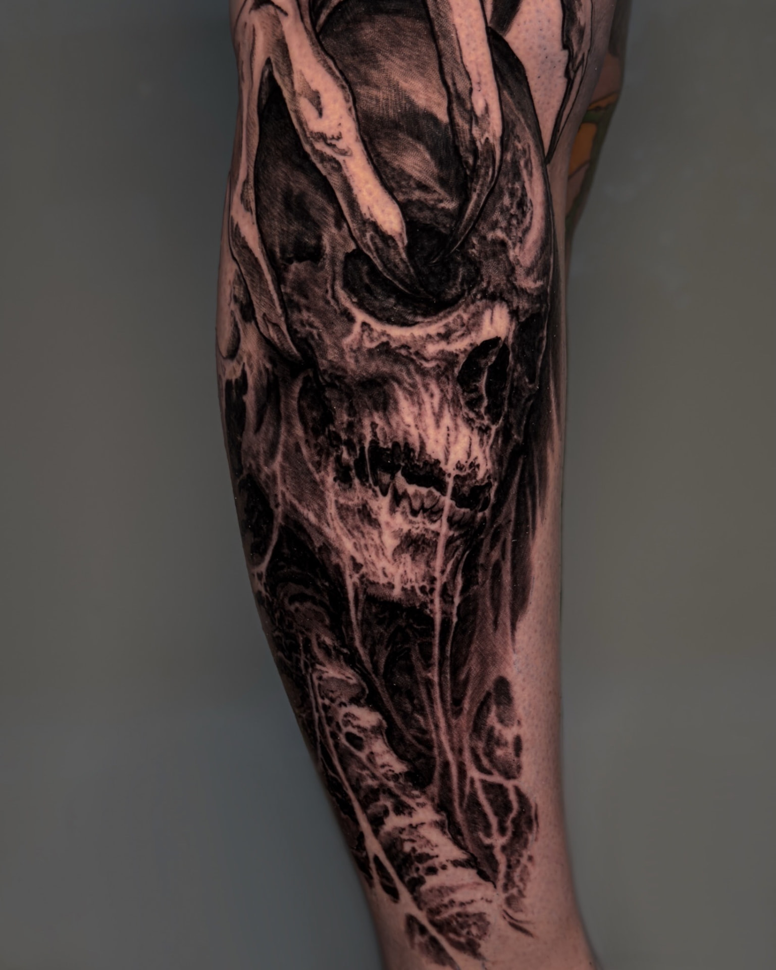 Black-and-grey skull and abstract forms leg tattoo by Andrew Stopay